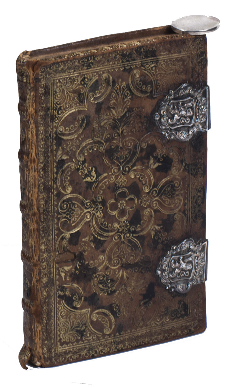 DAM, Jan Albertsz. van. - Nieuw geinventeerde koopmans comptoir- en schrijf-almanach, op het schrikkel-jaar onzes heeren J. Christi M DCC XII. Na de nieuwe styl. Versien met de jaarmarkten, paarde- beeste- en leer-markte, en de dageliksche uure van de maans op en ondergang.Amsterdam, the heirs of Albert Magnus, [1711 (for the year 1712)]. 12mo. Printed in red and black throught, the title-page with Magnus's woodcut device (Atlas with an armillary sphere on his shoulders), numerous typographical symbols in the text: for example a horse and a goat representing horse and other animal market days, moons in different phases, planetary signs and manicules (pointing hands). With a small etching of an angel (39 mm tall) holding a wreath, cut out of an unidentified source and loosely inserted between 2 blank pages at the end of the book. Contemporary, elaborately gold-tooled mottled calf over thin wooden boards by the so-called Art Book Bindery (1705-1741) in the style made famous by Albert Magnus himself, with more than 100 impressions of about a dozen stamps and one roll, gold-tooled board edges. Further with 4 silver anchor plates (2 on each board), each with the coat of arms of the States of Holland in a decorative cartouche, and each with a silver eye extending over the fore edge, with a silver combination stylus/lead pencil used to fasten the book through the eyes, gilt edges.